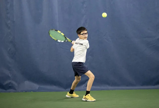 A young player hitting a forehand on an indoor court